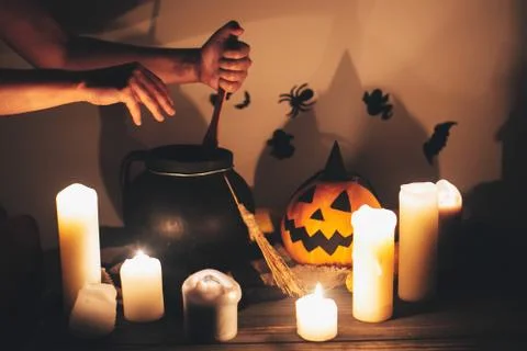 Witch hand boiling potion for spell, with jack o lantern pumpkin with candles Stock Photos