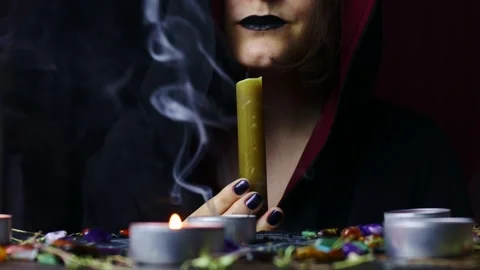 Witch hands performing a magic ritual blowing off a candle on a magical altar Stock Footage 242774125