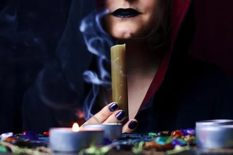 Witch hands performing a magic ritual blowing off a candle on a magical altar Foto stock