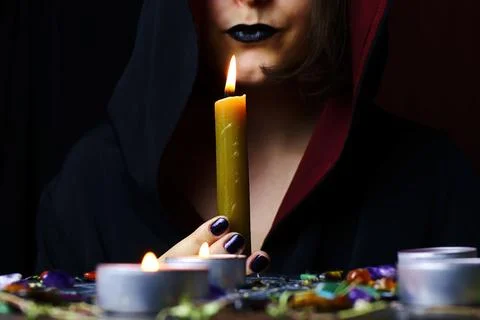Witch hands performing a magic ritual holding a candle on a magical altar Stock Photos