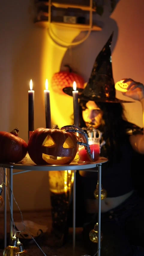 Witch holds glowing pumpkin light during festive Halloween celebration Stock Footage 345494309