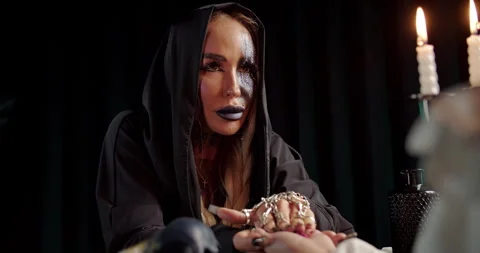 Witch interpreting wax shapes on clients palm after candle ritual Stock Footage 319606069