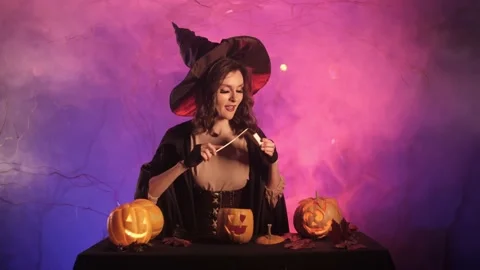 Witch lights a pumpkin for halloween Stock Footage 163752476