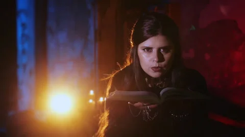 The witch looks into the camera and blows dust off a magic book. Stock Footage 285768068
