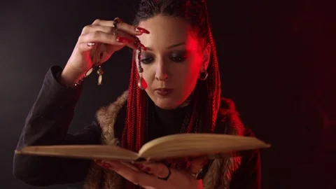 Witch with magic book and amulet telling spell in smoke Stock Footage 123961672