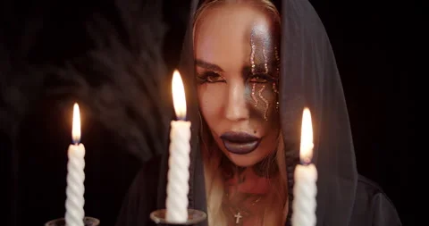 Witch with mystical makeup behind burning candles Stock Footage 319597375