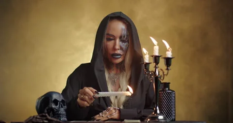 Witch performing candle ritual with burning candle in mystical yellow smoke Stock Footage 320016178