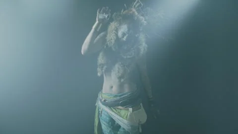 A witch performing a ritual dance under the spotlight in a dark room Stock Footage 259859806