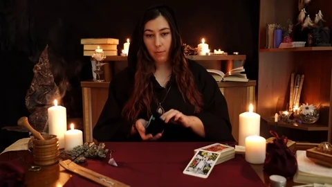 Witch puts ancient runes on table. Tarot cards, candles on mystic background. Video stock 108010548