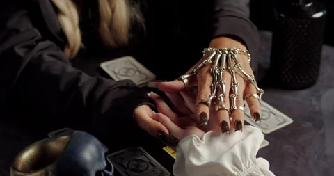 Witch reading clients palm during mystical fortune-telling ritual Stock Footage 320008404