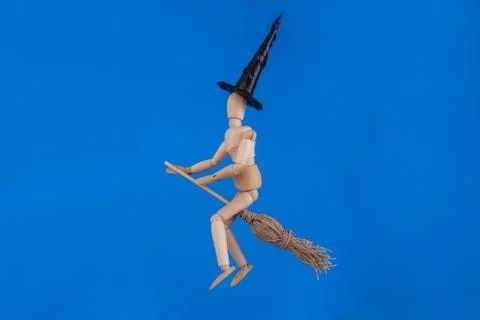 Witch riding a broom on solid blue background 库存照片
