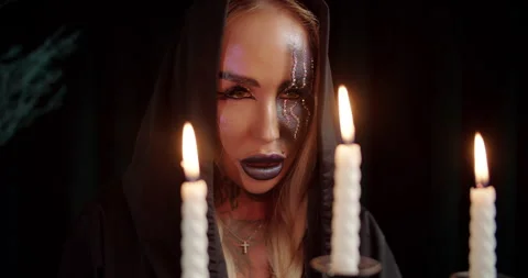 Witch staring through candle flames in dark room Stock Footage 319597228