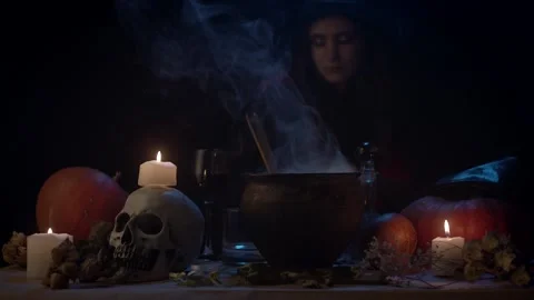 Witch at table in dark with steaming cauldron Stock Footage 141292799