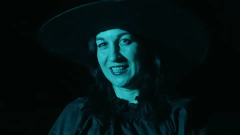 Witch wearing black hat changing facial expressions on black background Stock Footage 297091130