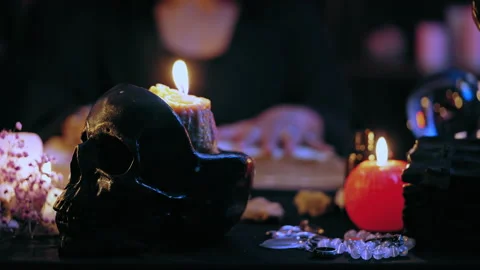 Witch working with spell book in front of spooky skull candle holder, rituals Stock Footage 201331411