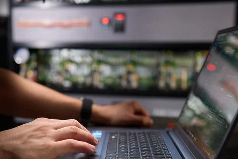 Within a tech environment, a professional is busily working on a laptop while Stock Photos