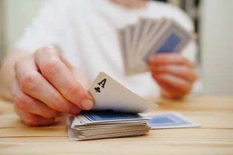 Without a face. Hands of a man in a white t-shirt with cards during the game. Stock Photos