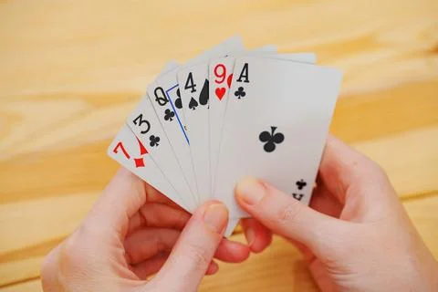 Without a face. Hands of a man in a white t-shirt with cards during the game. Stock Photos