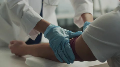 Without a face, a laboratory assistant in the clinic puts a tourniquet on the Video stock 150335390