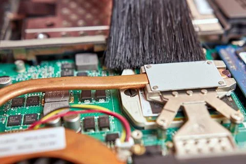 The wizard cleans the laptop's cooling system with a brush and a vacuum cleaner. Stock Photos