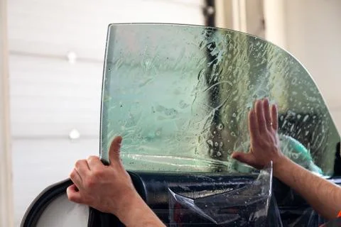 The wizard for installing additional equipment sticks a tint film on the side Stock Photos