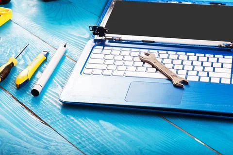 Wizard repairs laptop with tools and hands on the blue wooding table. top vie Stock Photos