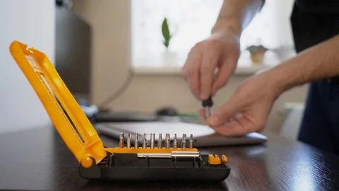 The wizard uses a screwdriver to twist the screw on the lid of the notebook. Stock Footage 87470738