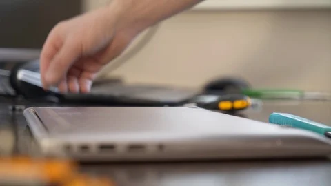 The wizard uses a screwdriver to twist the screw on the lid of the notebook. Stock Footage 87520356