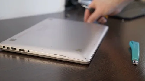 The wizard uses a screwdriver to unscrew the screw from the laptop cover. Laptop Stock Footage 87448075