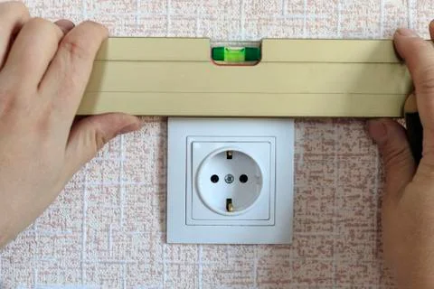 The wizard using the level set the outlet. he is white. close-up Stock Photos