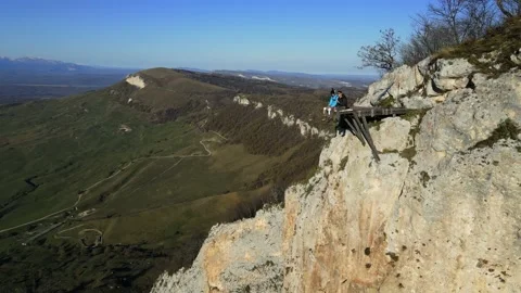 Wo men are sitting on the edge of a cliff and talking Stock Footage 170904319