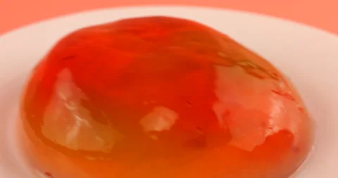 Wobbly multi-colored berry gelatin jelly on a white plate on a pink background. Stock Footage 219968045
