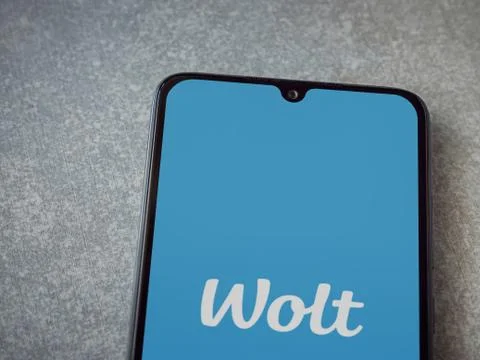 Wolt app launch screen with logo on the display of a black mobile smartphone  Foto stock