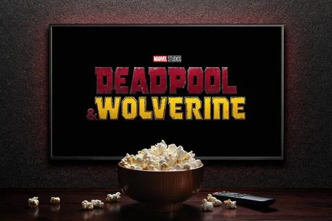 Wolverine and Deadpool trailer or movie on TV screen. TV with remote control and Stock Photos