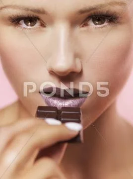 A woman about to eat a chocolate bar Stock Photos