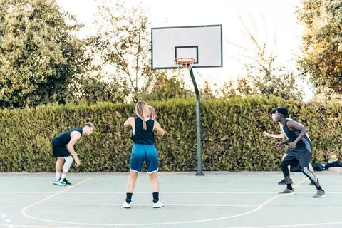 Woman about to shoot a three-pointer during an outdoor basketball match Stock Photos