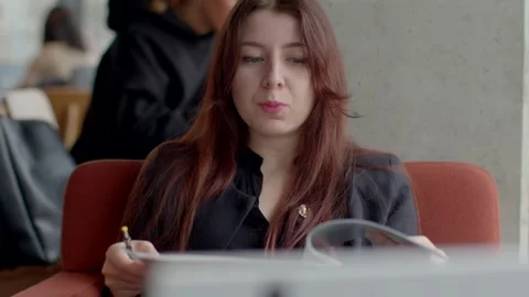 A woman is absorbed in reading documents while seated in a cafe setting Stock Footage 311204963