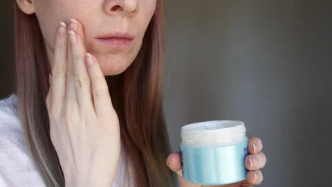 Woman with acne and rosacea uses cream on her skin Stock Footage