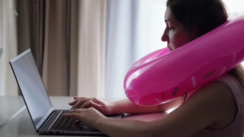 Woman actively types on laptop using inflatable ring as neck pillow Stock Footage 302154820