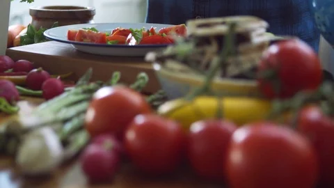 Woman adding basil leaves and olive oil on sliced tomatoes Stock Footage 70109291