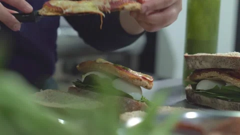 Woman adding basil sauce to a vegetarian sandwich Stock Footage 240785587