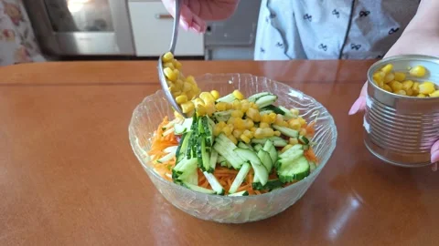 Woman Adding Canned Corn to Fresh Vegetable Salad Stock Footage 339404170