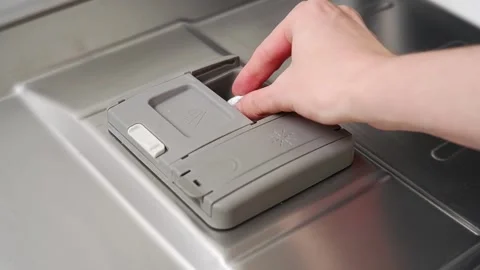 Woman adding detergent tablet and rinse aid into dishwasher compartment Video stock 304363085