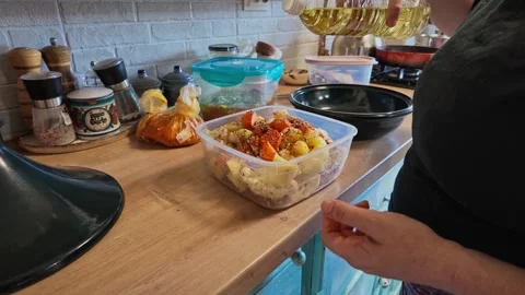 Woman Adding Oil to Vegetable Mix for Tajine Recipe in Her Kitchen Stockbeeldmateriaal 341669548