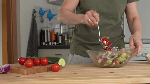 Woman adding olive oil and mixing greek salad at home kitchen Stock Footage 242510934