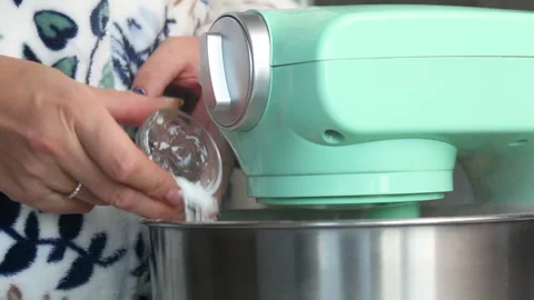 A woman is adding powdered sugar to the planetary mixer bowl. Makes meringue  Stock Footage 210786869