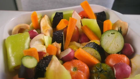 Woman adding salt pepper to fresh vegetables fruit herb on baking sheet to bake. Stock Footage 312460065