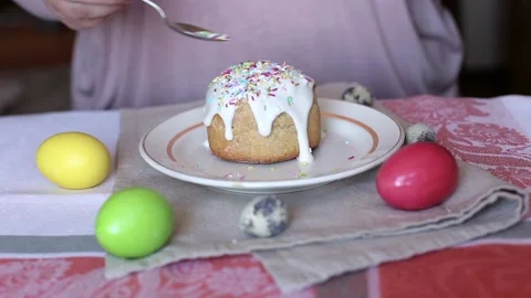 Woman adding sprinkles on the top of the Easter cake. Colored eggs on a table. Stock Footage 114291410