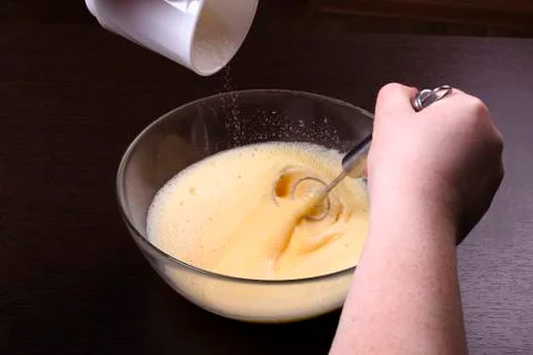 Woman is adding sugar to the egg mixture Stock Photos