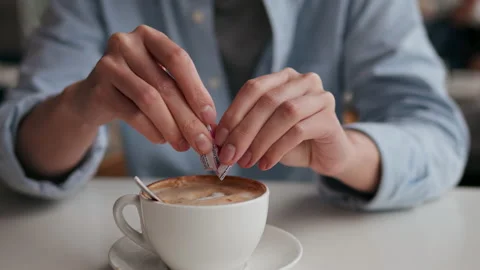Woman adding sugar sticker to a cup of cappuccino coffee, Young woman drinki Stock Footage 234425324